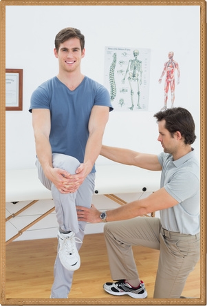 Male therapist assisting a happy young man with stretching exercises in the medical office