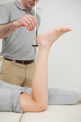 Practitioner using a reflex hammer in a medical room