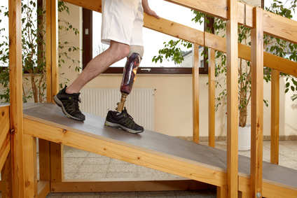 Male prosthesis wearer training to descend a slope in a speical parcour or interior area where surfaces have been laid out to simulate realistic environmental situations