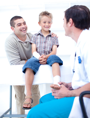 Doctor bandaging a patient's foot with his father in hospital