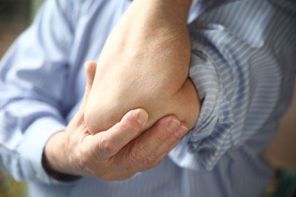 Close-up of a supportive hand holding an arm, a technique to manage tennis elbow discomfort, available at our Flint, MI clinic.