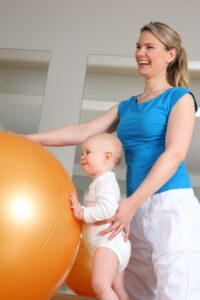 Child performing a therapeutic exercise to enhance flexibility and recovery under therapist supervision.