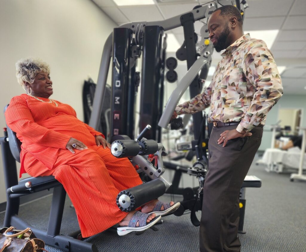 Dr. Jerome Adams talking with a patient during leg-strengthening exercises at Horizon Physical Therapy in Flint, Michigan